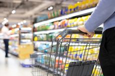 Woman pushes shopping cart in supermarket.