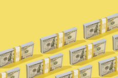 One hundred dollar banknotes lined up on yellow background.