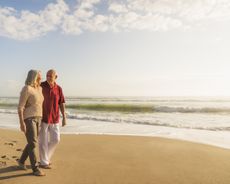 Senior couple walking on beach.