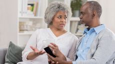 An older couple have a serious talk while sitting on the sofa together.