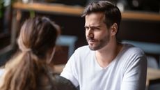 A man wears a doubtful expression as he looks at his dinner companion.