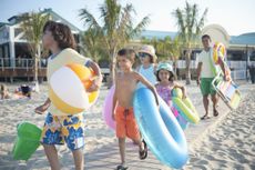 A family walks on a small boardwalk to go to the beach.