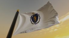 image of Massachusetts flag on a pole against a sunset sky